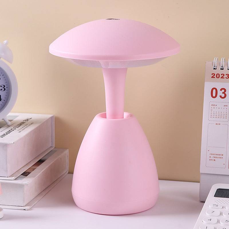 Pink bedroom eye protection small night lamp with a modern mushroom-shaped design, placed on a desk. Ideal for soft ambient lighting.